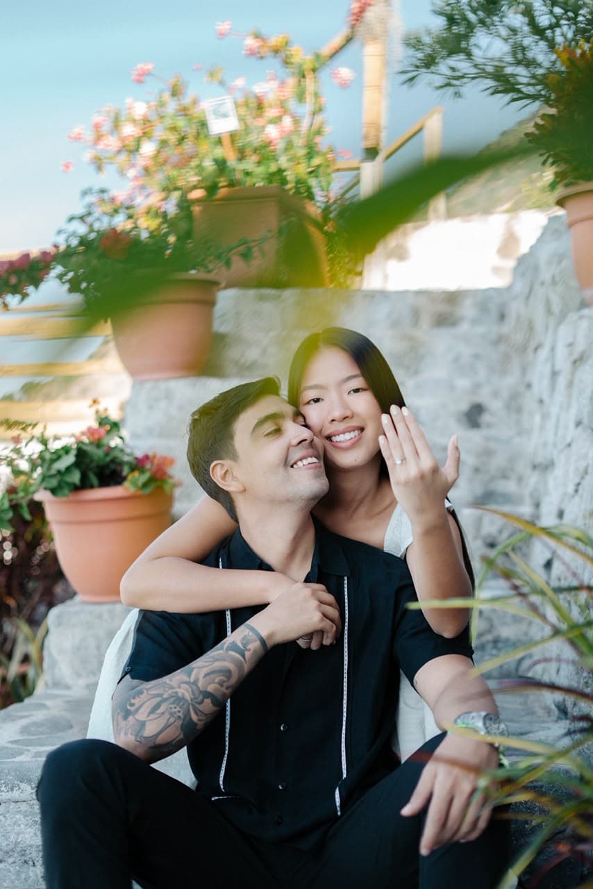 Leonardo y Emily sentados en una escalinata rodeada de flores